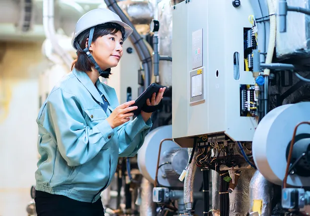 女性技術者がタブレットを操作し、設備を点検している。